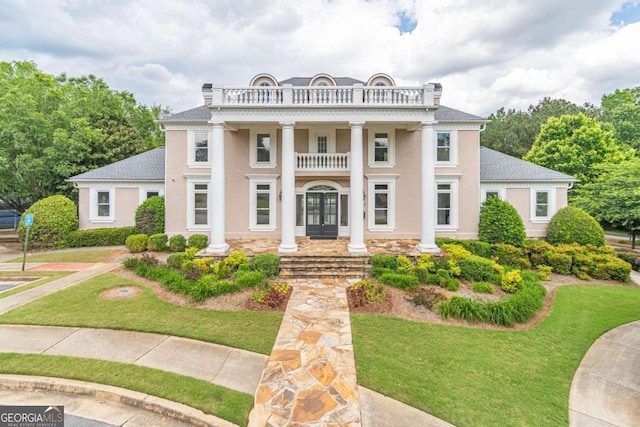 greek revival house with a balcony, french doors, and a front lawn