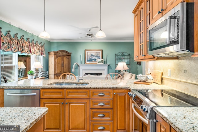 kitchen featuring appliances with stainless steel finishes, a sink, brown cabinetry, ceiling fan, and tasteful backsplash