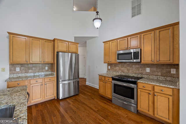 924 Vinings Dr, Winder, GA 30680 - kitchen featuring stainless steel appliances, a high ceiling, dark wood-style floors, tasteful backsplash, and light stone countertops