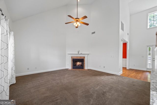 924 Vinings Dr, Winder, GA 30680 - unfurnished living room with high vaulted ceiling, carpet flooring, ceiling fan, baseboards, and a tiled fireplace