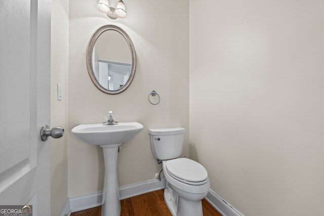 924 Vinings Dr, Winder, GA 30680 - half bathroom with wood finished floors, toilet, baseboards, and a sink