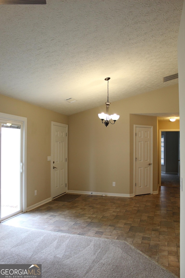 spare room with a chandelier, baseboards, and a textured ceiling