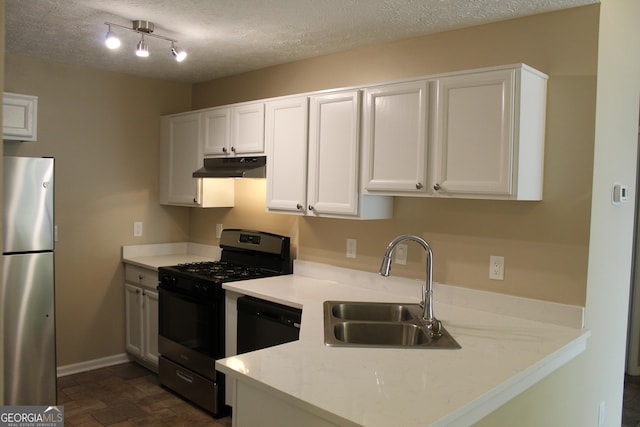 kitchen with freestanding refrigerator, under cabinet range hood, gas stove, a sink, and white cabinets