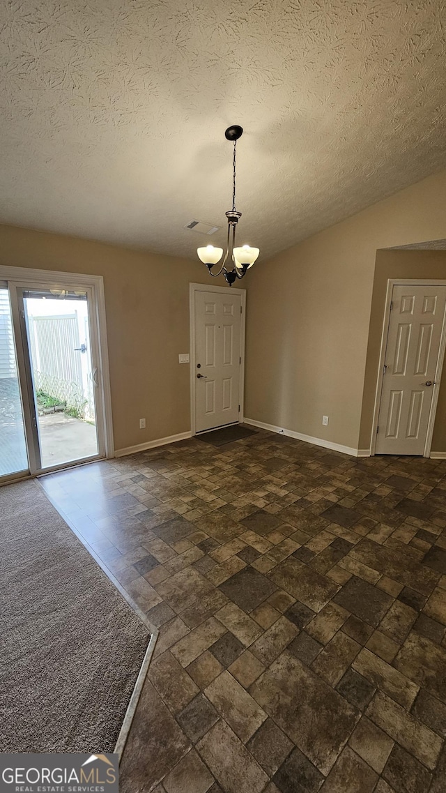 spare room featuring a chandelier, baseboards, and a textured ceiling