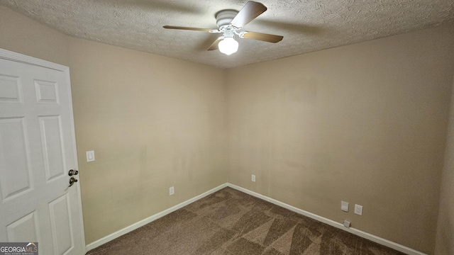 empty room featuring ceiling fan, dark carpet, a textured ceiling, and baseboards