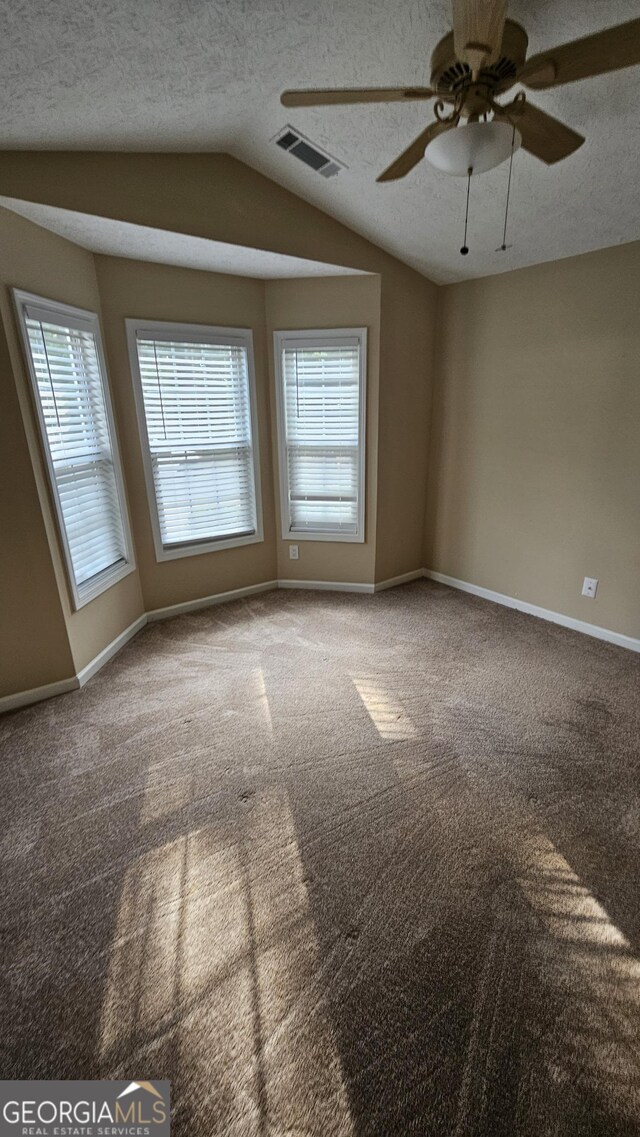 carpeted spare room featuring lofted ceiling, baseboards, ceiling fan, and a textured ceiling
