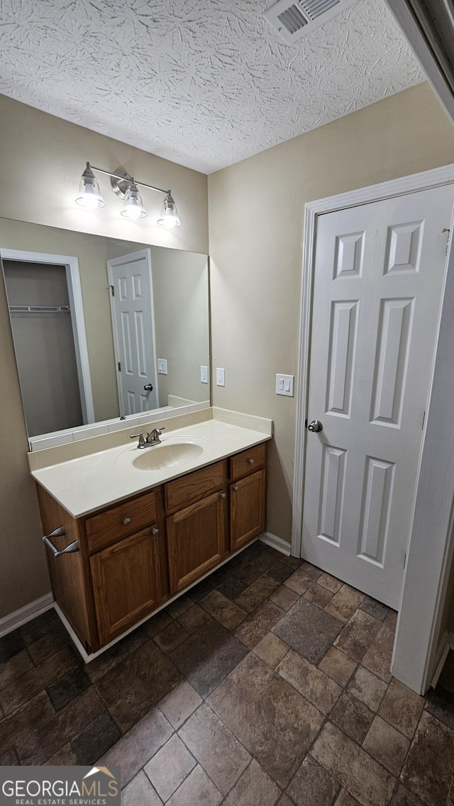 bathroom with stone tile flooring, vanity, and baseboards
