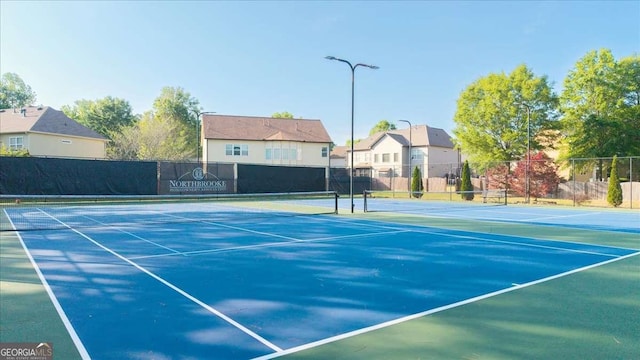 view of tennis court featuring fence and a residential view