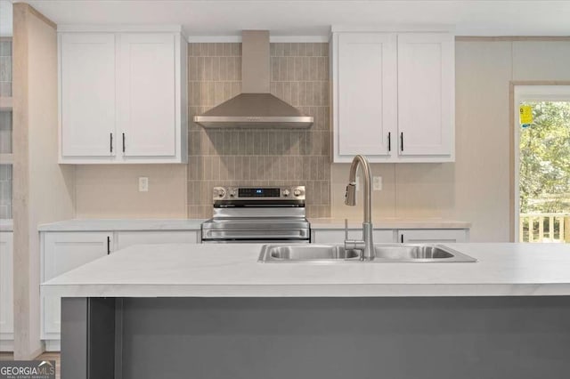 kitchen with electric range, wall chimney range hood, a sink, light countertops, and white cabinets