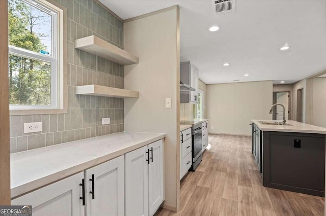 kitchen featuring open shelves, decorative backsplash, light wood finished floors, light countertops, and plenty of natural light