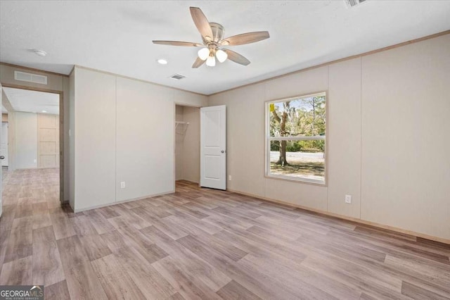 unfurnished bedroom with light wood-style floors, ceiling fan, a closet, and crown molding