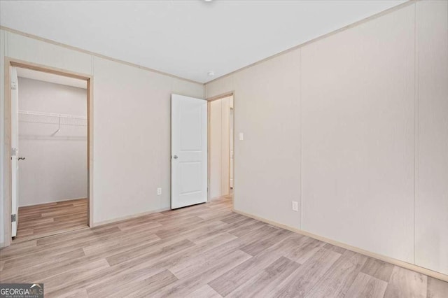 unfurnished bedroom with light wood-type flooring, a closet, and a walk in closet