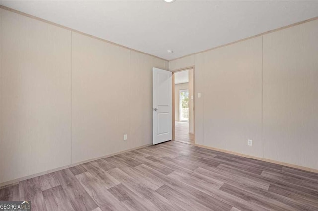 unfurnished room with light wood-style flooring, crown molding, and baseboards