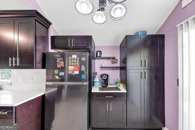 kitchen featuring freestanding refrigerator, light countertops, a chandelier, and dark brown cabinets