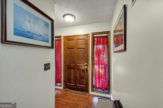entryway featuring a textured ceiling, wood finished floors, and baseboards