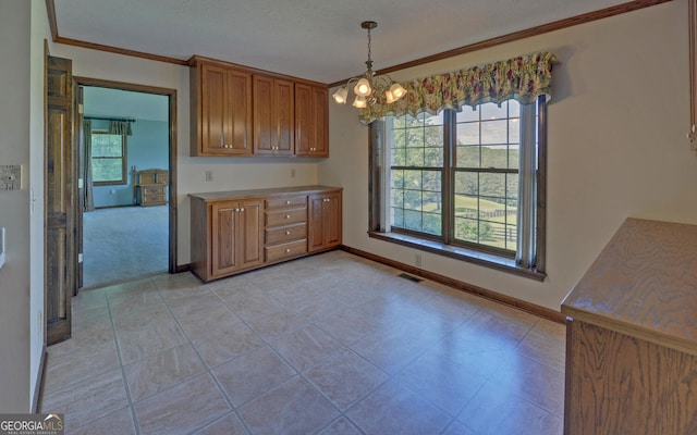 kitchen with brown cabinets, baseboards, crown molding, a chandelier, and hanging light fixtures