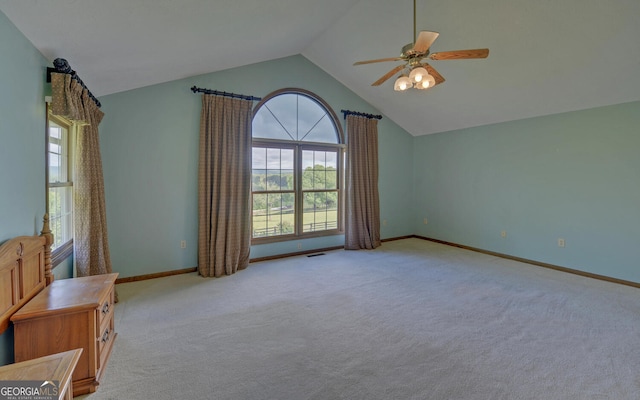 unfurnished bedroom featuring light carpet, vaulted ceiling, baseboards, and ceiling fan