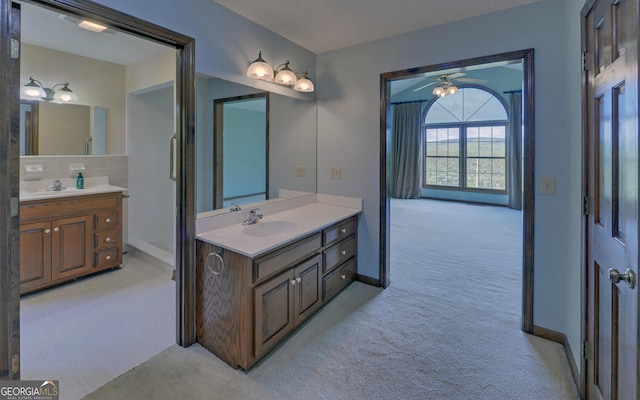 bathroom featuring two vanities, ceiling fan, backsplash, and baseboards