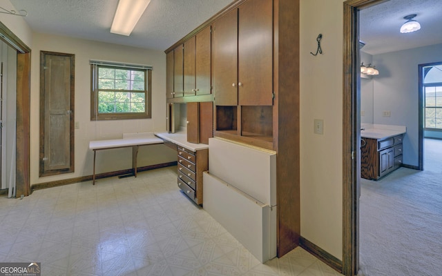 kitchen featuring a textured ceiling, healthy amount of natural light, light countertops, and baseboards