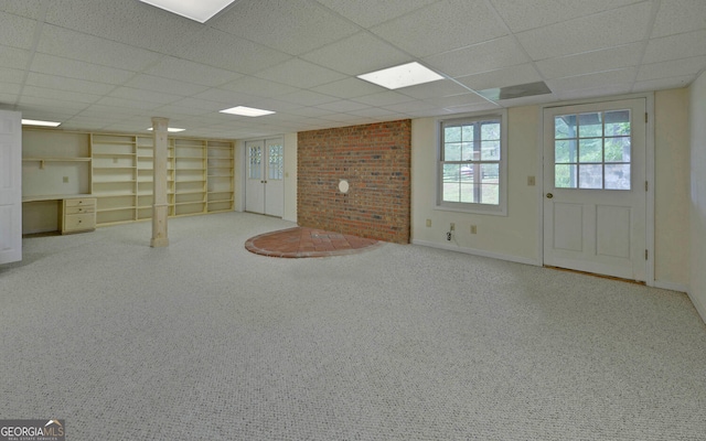 below grade area with a paneled ceiling, carpet floors, built in features, and baseboards