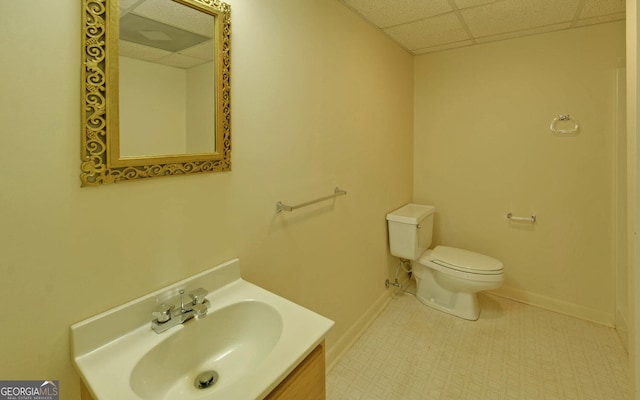 bathroom with vanity, toilet, baseboards, and a drop ceiling