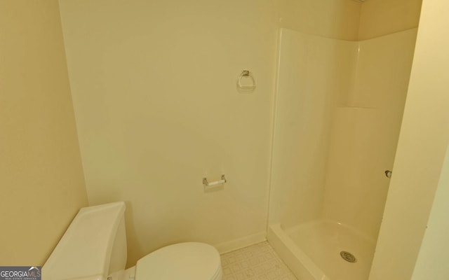 bathroom with tile patterned floors, toilet, and a shower
