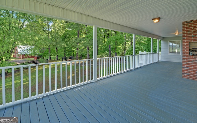 deck featuring view of scattered trees and a lawn
