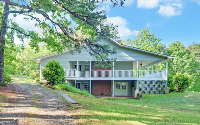 rear view of house with a lawn, driveway, brick siding, and a deck