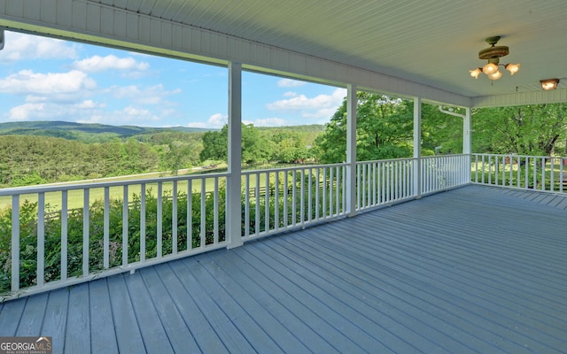 wooden terrace with a view of trees and a ceiling fan