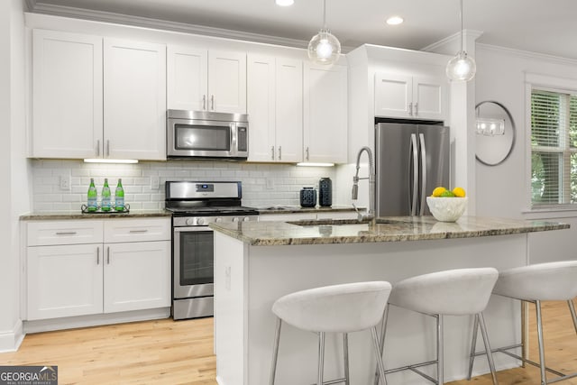 770 Ormewood Ave SE, Atlanta, GA 30312 - kitchen featuring stainless steel appliances, a sink, backsplash, white cabinetry, and a kitchen bar