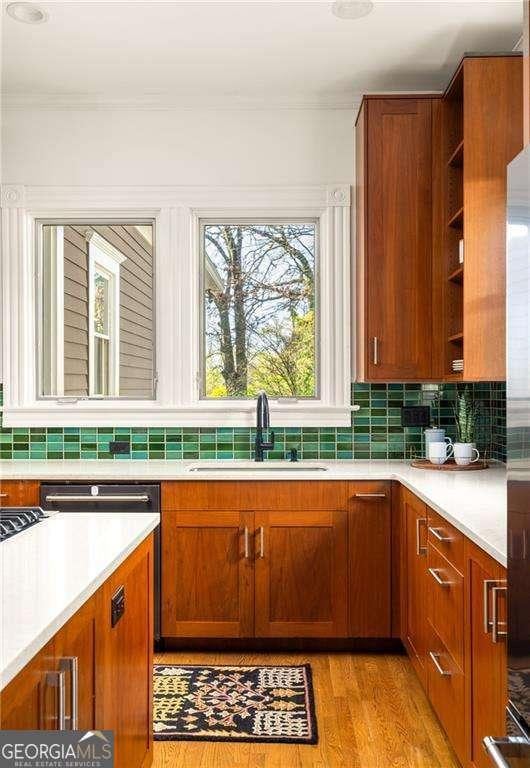 629 Hansell St SE, Atlanta, GA 30312 - kitchen featuring a sink, backsplash, light countertops, light wood-style flooring, and crown molding