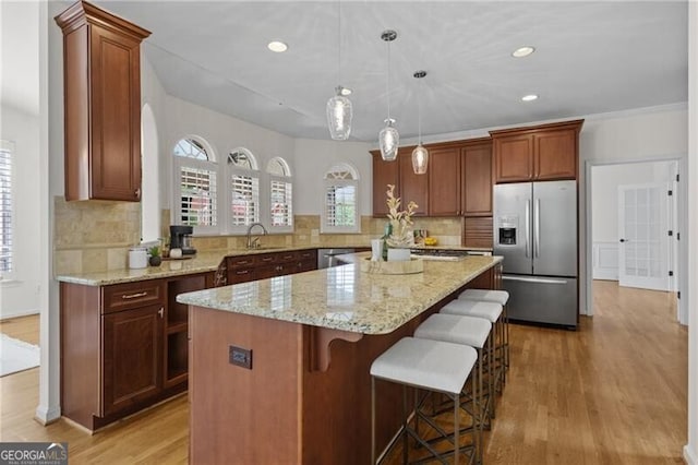 kitchen with stainless steel appliances, light wood-style flooring, a center island, backsplash, and recessed lighting