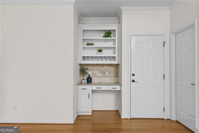 bar area with light wood-type flooring, ornamental molding, and tasteful backsplash