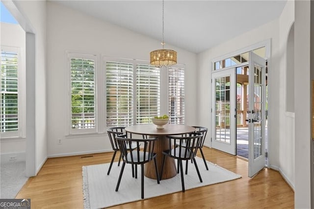 dining area with vaulted ceiling, french doors, light wood-type flooring, baseboards, and a chandelier