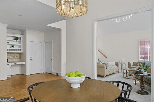 dining room with a chandelier, wood finished floors, and crown molding