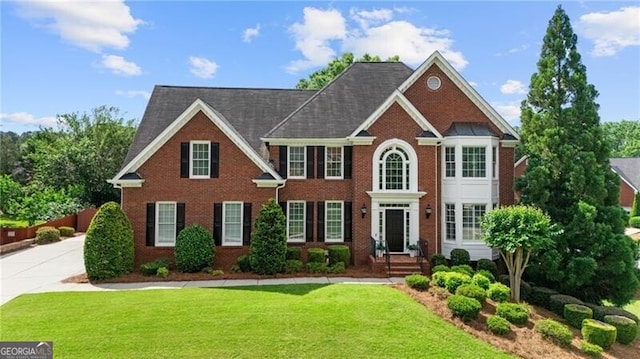 colonial inspired home with brick siding and a front lawn