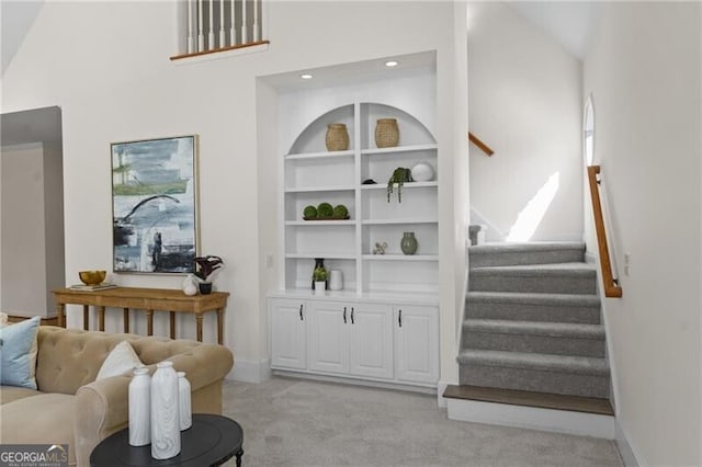 living room featuring light carpet, stairs, baseboards, and lofted ceiling