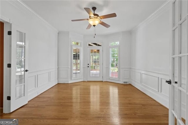 spare room with wood finished floors, ceiling fan, a decorative wall, a wainscoted wall, and ornamental molding