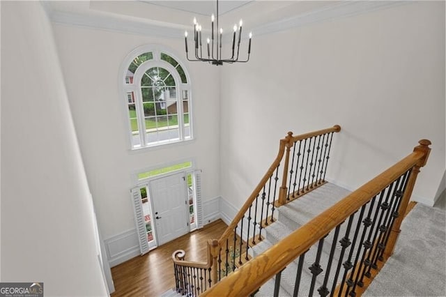 entrance foyer featuring a chandelier, wood finished floors, crown molding, and stairway