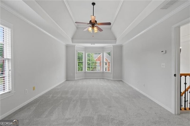 spare room with carpet flooring, a ceiling fan, a tray ceiling, baseboards, and ornamental molding