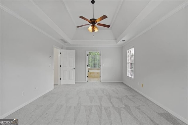 empty room with a tray ceiling, ceiling fan, carpet flooring, and baseboards