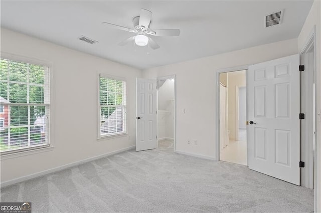 unfurnished bedroom featuring baseboards, carpet, a walk in closet, and ceiling fan