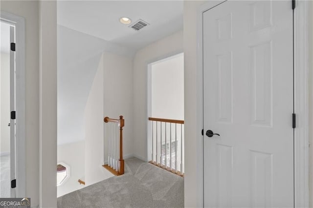 hall featuring carpet floors and an upstairs landing