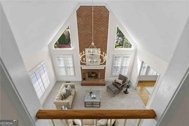 living room with high vaulted ceiling, a chandelier, and a fireplace