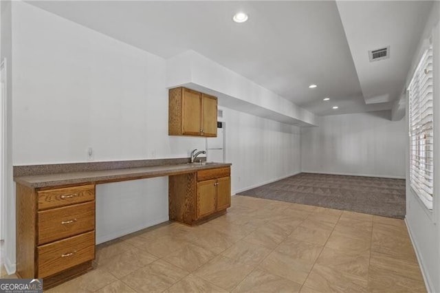 below grade area featuring a sink, recessed lighting, light colored carpet, and baseboards