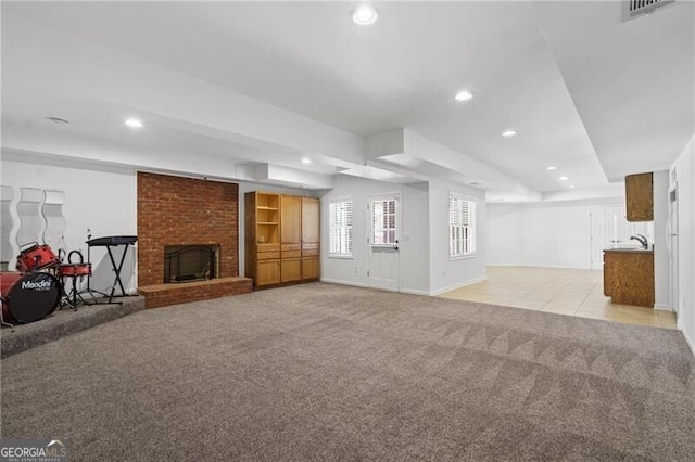 unfurnished living room with light colored carpet, recessed lighting, a brick fireplace, baseboards, and a sink