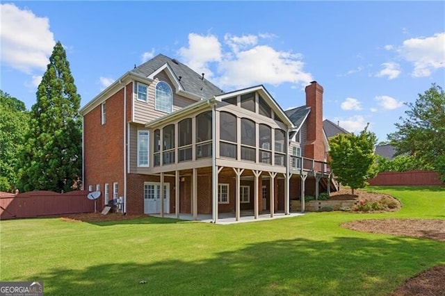 rear view of property featuring a sunroom, a patio area, brick siding, and a chimney
