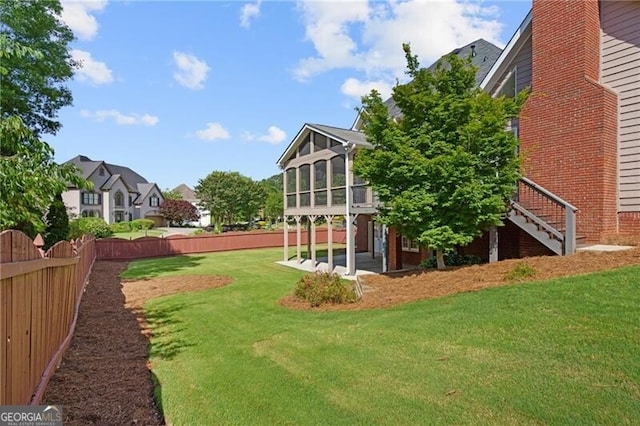 view of yard featuring a sunroom, stairway, a patio, and a residential view