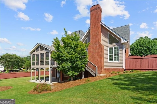rear view of property featuring a sunroom, stairs, and a chimney