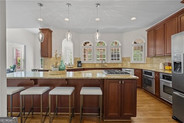 kitchen with stainless steel appliances, decorative backsplash, light stone counters, and recessed lighting